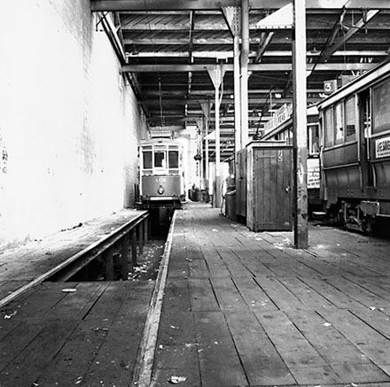 d. Interior of Tram Barns, parked tramcars, motor vehicles, tramlines