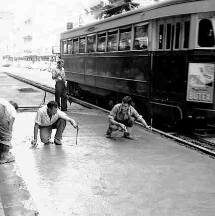 d. Workmen paving the road between the tram lines and the footpath