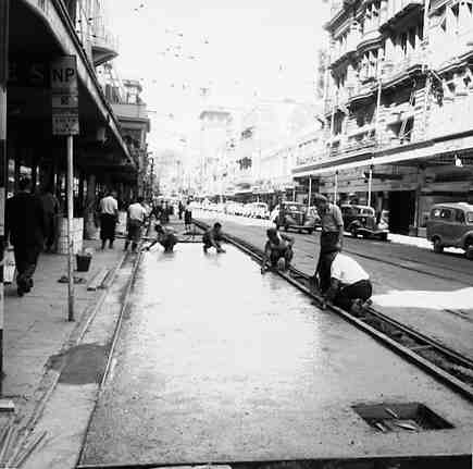 e. Workmen paving the road between the tram lines and the footpath