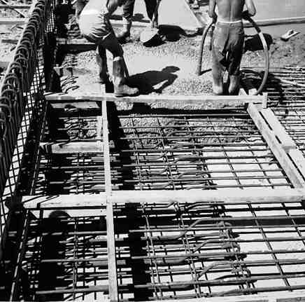 a. Workmen pouring concrete onto reinforcing 