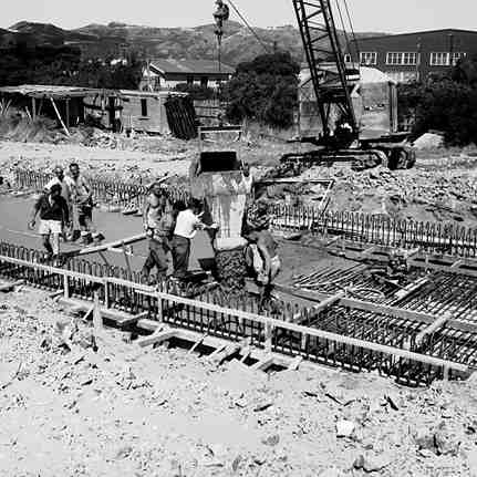 b. Workmen pouring concrete onto reinforcing 
