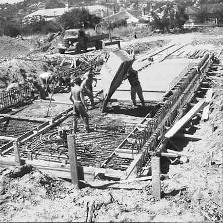 a. Workmen pouring concrete onto reinforcing
