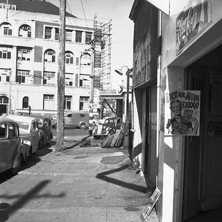 b. Service Station on corner of Whitmore Street and Customhouse Quay, motor vehicles, poster advertising ' Luck for Mum ' competition, May 4th