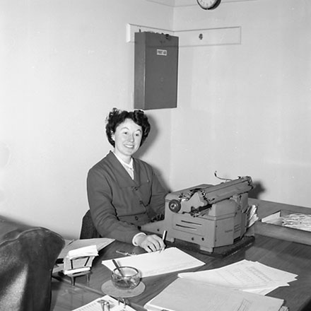 b. Woman sitting at desk with typewriter