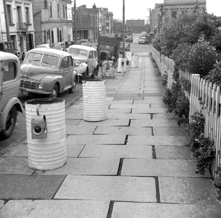 b. Footpath, motor vehicles, tramcars, white drums and lights marking area of proposed street works