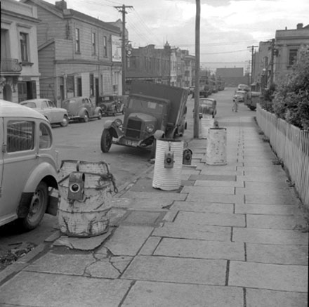 c. Footpath, motor vehicles, tramcars, white drums and lights marking area of proposed street works