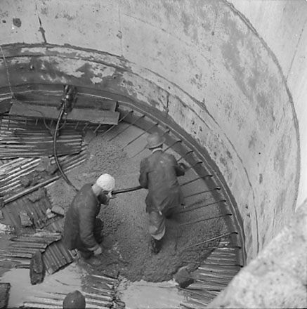 a. Views of construction, workmen using overhead crane to pour concrete