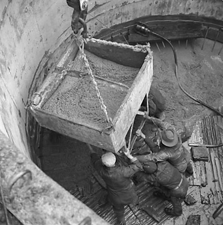 f. Views of construction, workmen using overhead crane to pour concrete