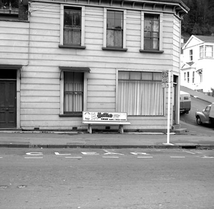 d. Unidentified location, wooden bus stop seat, advertising for Huttons Swan Meats and Small Goods