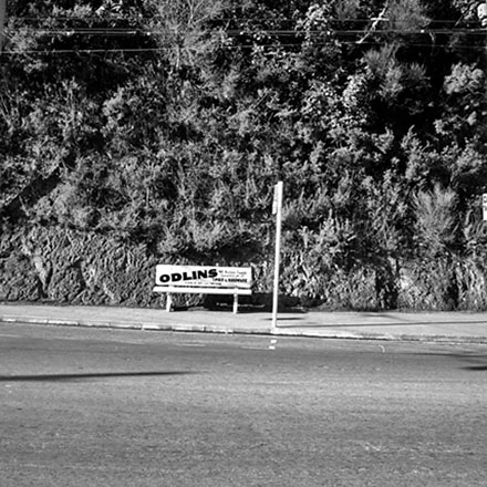 a. Seat at bus stop, advertising Odlins Hardware and Timber