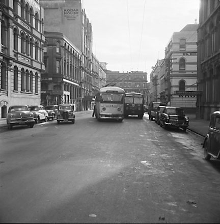 a. Trolly bus attempting to pass a diesel bus. Chews Lane on the left, Kodak Building in the background. Motor Vehicles