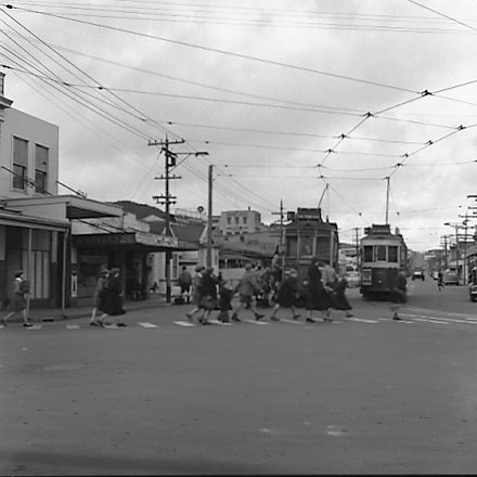 a. School children crossing pedestrian crossing, corner of Adelaide Road and Rugby Street. Tramcars in background