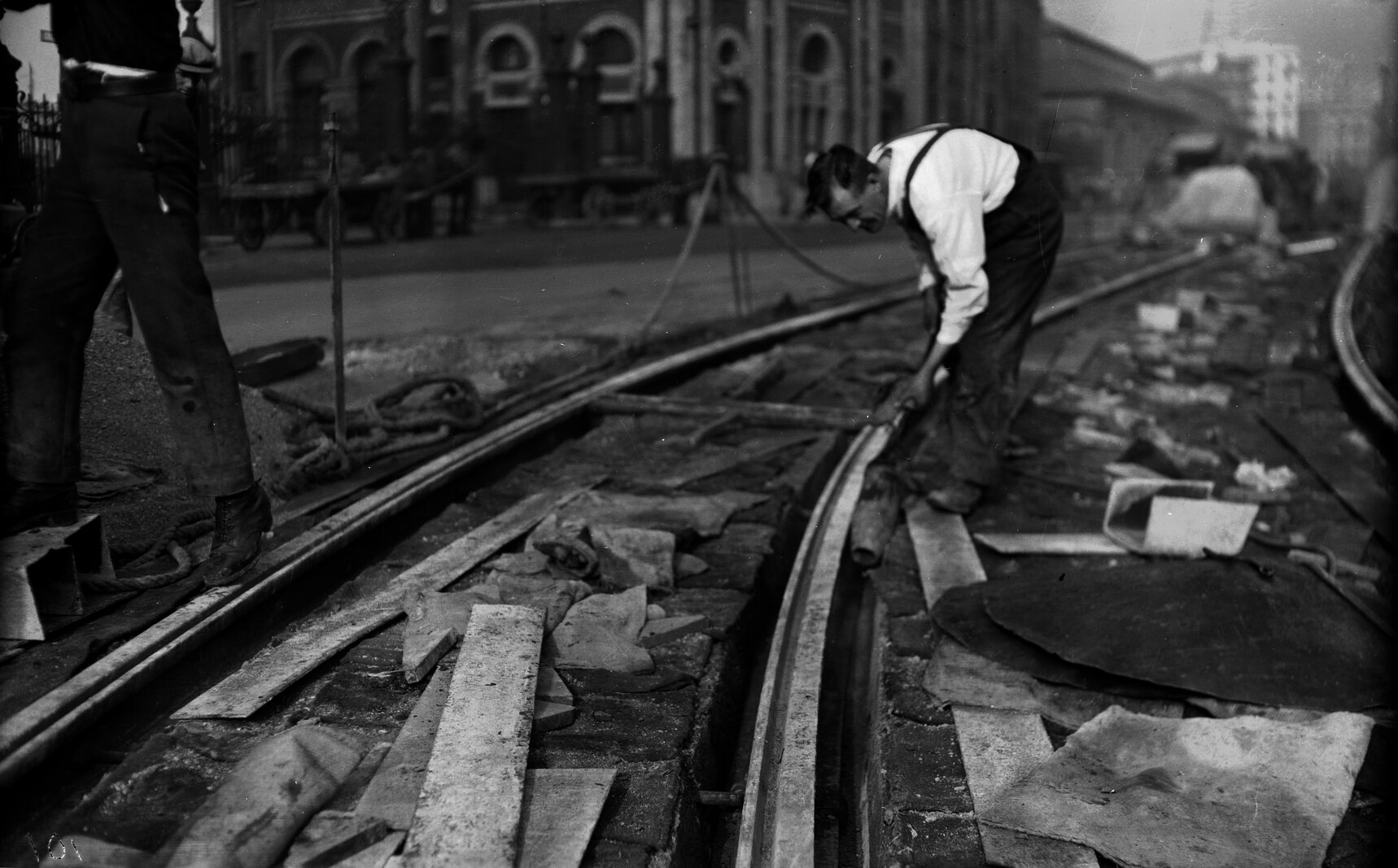 Corner of Customhouse Quay and Whitmore Street, workman drying out under tram rail by flame torch