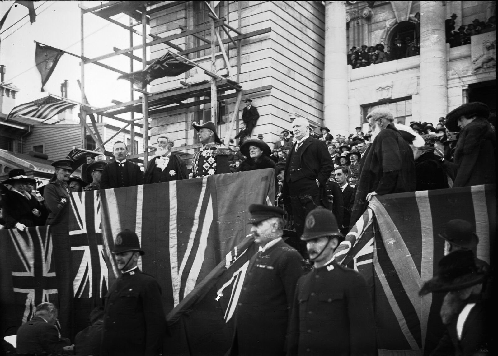 Dignitaries address a crowd of people in front of the Parliament Buildings