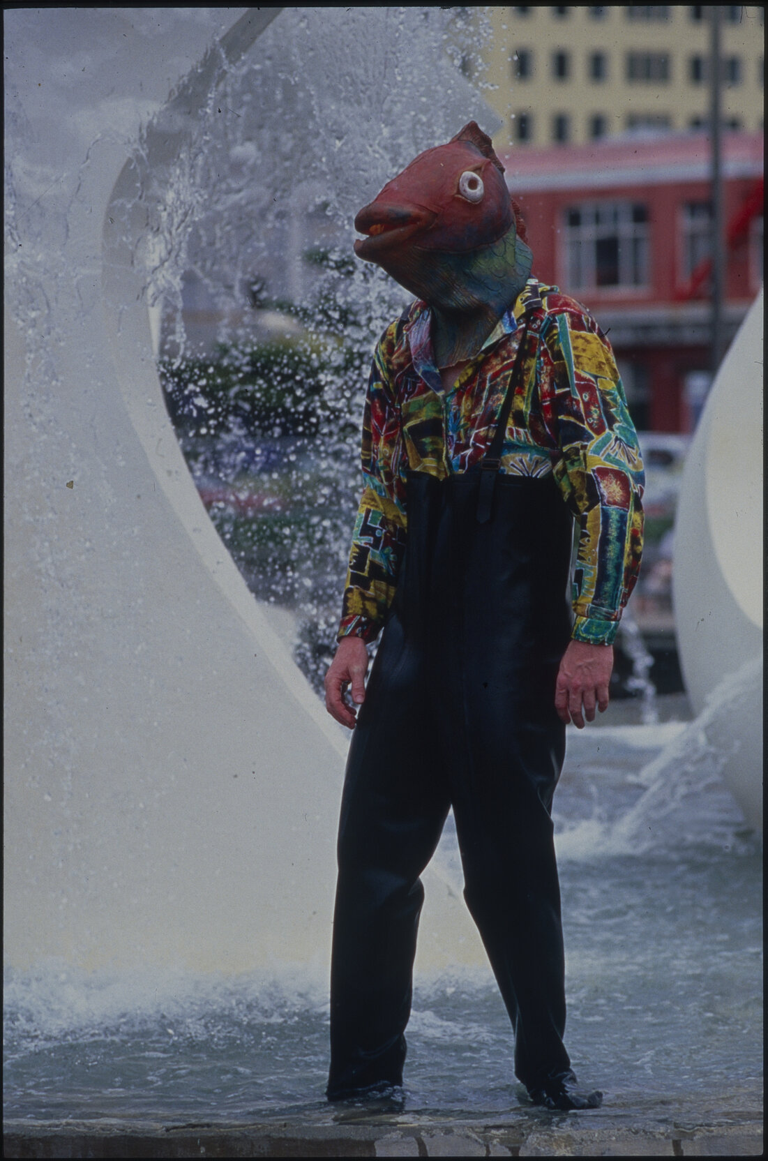 Person standing in "Albatross" fountain with a fish mask on their head