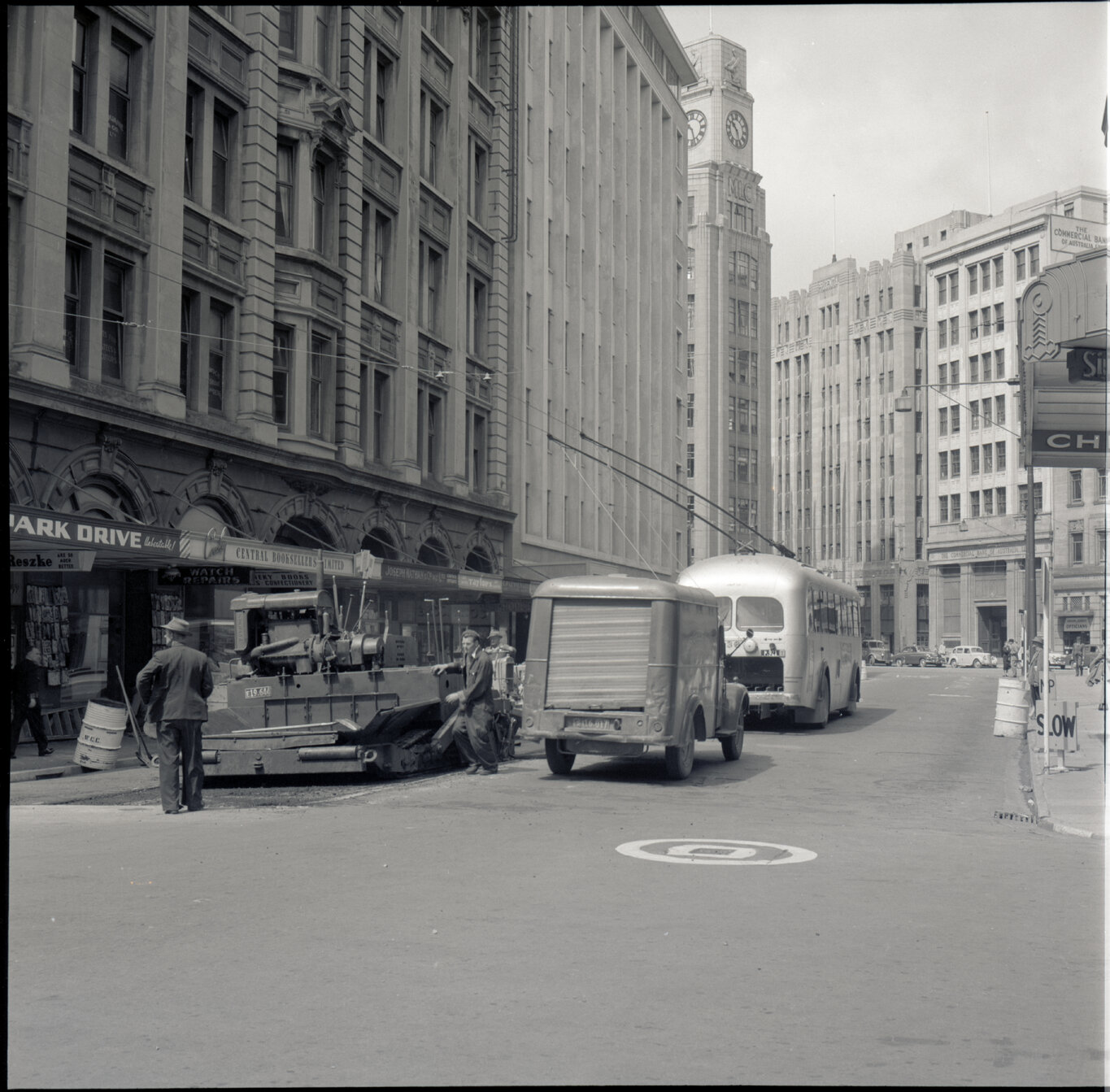 d. Various stages of asphaltic road surfacing by Council workmen, Lambton Quay end of Featherston Street. People passing by have stopped to watch work in progress. Trolly buses in background