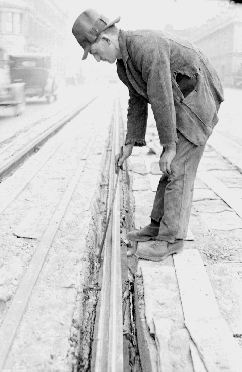 Workman compacting fill around tram rail