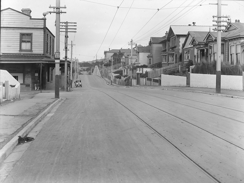 At Howard Street intersection, tram tracks in road, area of wooden dwellings and Fernleaf Dairy on corner. Photograph of new asphaltic concrete surface, Wallace Street, February 1926