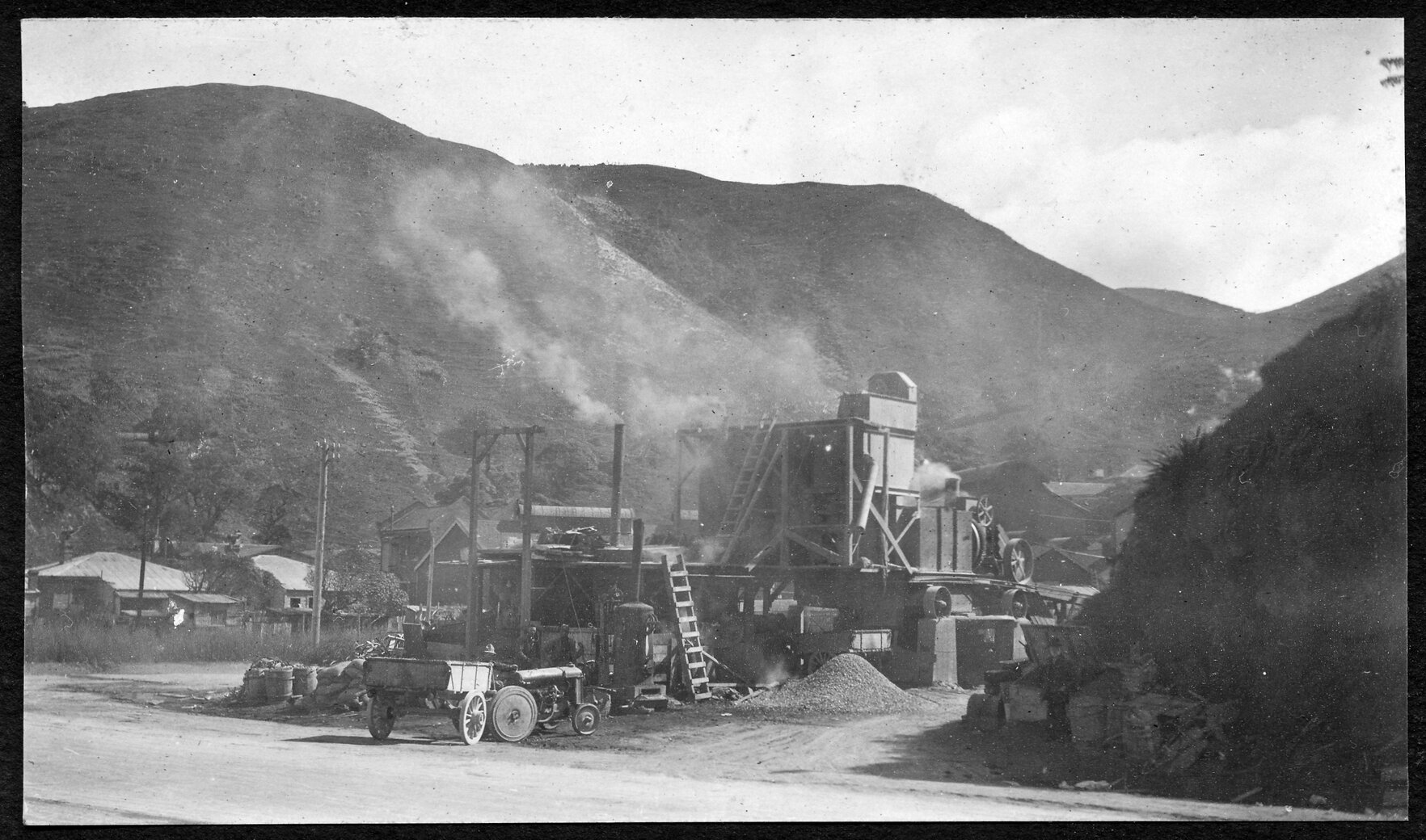 Workmen are spreading new asphalt in process of road sealing. Supervisor stands to right.