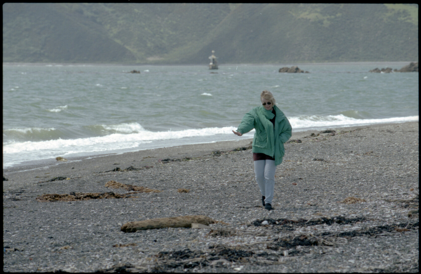 Woman on Seatoun beach with Steeple Rock Lighthouse in background