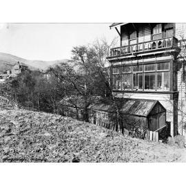 Two storey wooden dwelling, next to built up area of ground