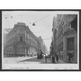 The old Bank of New Zealand building stands on the corner of Customhouse Quay and Lambton Quay. A tram is about to enter the intersection. Motor vehicles in the background. 