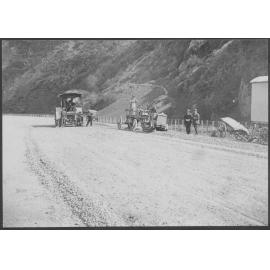 Road surface is being prepared for resurfacing, steam roller is in the background.