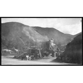 Workmen are spreading new asphalt in process of road sealing. Supervisor stands to right.