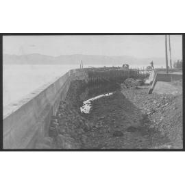 Construction of seawall, workmen in background.