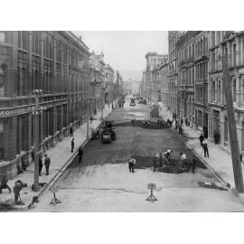 Elevated view of Victoria Street with alsphatic concrete paving in progress, number of workmen and equipment, Victoria Street, March 1926