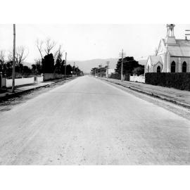 Photograph of the new alsphaltic concrete surface on High Street, previously identified as Main Hutt Road . It is a residential area with a wooden church is on the right hand side, High Street, Lower Hutt, October 1925